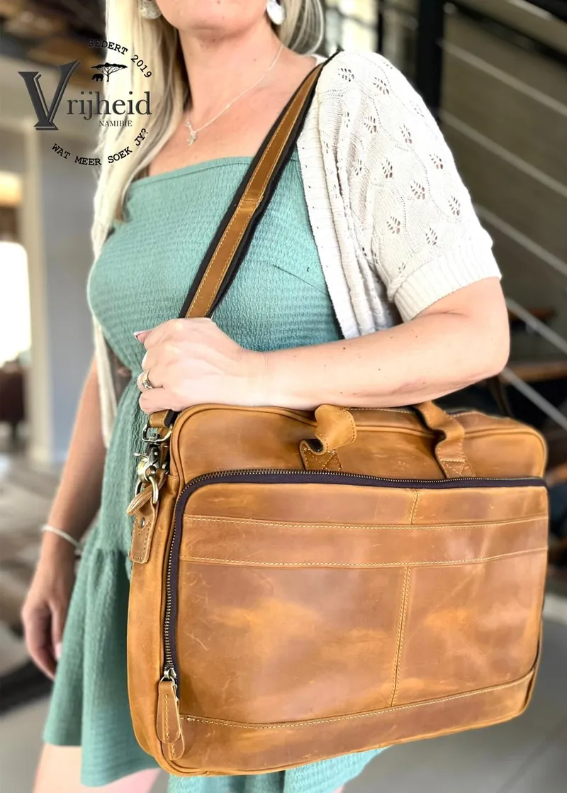 A woman carrying a tan leather laptop bag on her shoulder